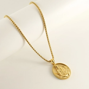 Collier doré classique avec médaillon religieux ovale sur une surface blanche élégante