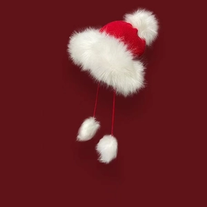 Detail of red knitted winter hat with fluffy white faux fur trim and festive pom-poms