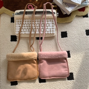Détail de sacs bandoulière en suédine kaki et rose avec bordure en polaire douce au sol