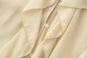 Detailed view of apricot V-neck blouse featuring delicate stitching and pearl buttons