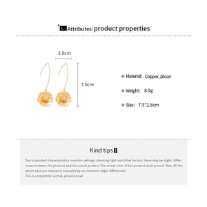 Détail macro de boucles d'oreilles fleur dorées en zircon, 7,5cm par 2,8cm, en cuivre