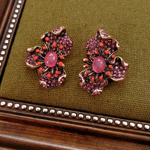Gros plan sur des boucles d'oreilles fleur vintage en résine avec strass roses et or
