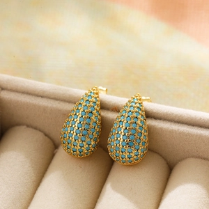 Detailed view of teardrop stud earrings with blue beads in a beige velvet jewelry box