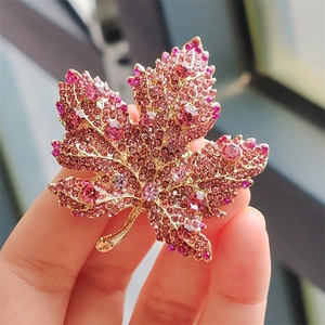 Macro detail of gold maple leaf brooch with pink gradient crystals and rhinestones