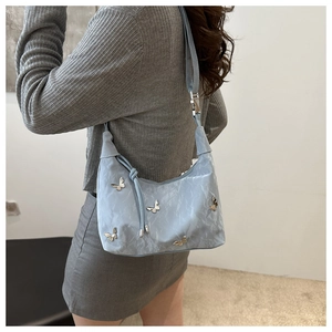 Detail of light blue wrinkled fabric shoulder bag with silver 3D metal butterfly ornaments
