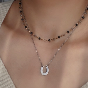 Close-up of a double-layered U-shape horseshoe necklace worn by a fashion model