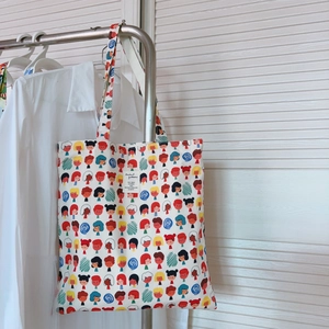 Détail du sac cabas blanc en coton avec motifs imprimés de personnages sur un cintre