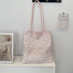 Detailed macro view of pink lace patchwork tote bag with sparkling sequins and brand label