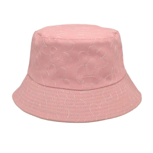 Détail d'un bob en coton rose avec broderies de marguerites blanches pour la protection solaire