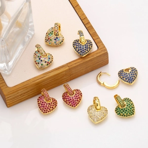 Macro detail of colorful zircon micro-pave heart earrings on a wooden jewelry display stand