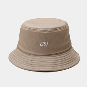 Detailed view of khaki canvas bucket hat with white 1987 embroidery and stitched brim