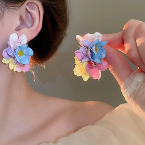 Close-up of vibrant multi-color 3D floral earrings with layered fabric petals worn by model