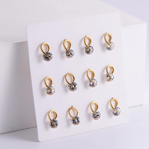 Sparkling set of 12 gold plated stud earrings with clear zircon stones on white cubes