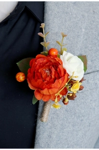 Close-up of handmade wedding boutonniere with orange peony and white rose on a grey suit