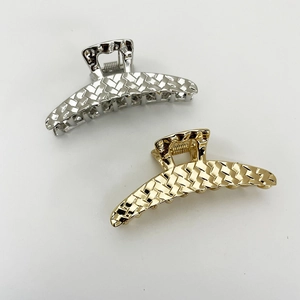 Detail of gold and silver hair claws with woven texture and curved metal design