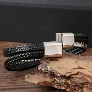Men's multilayer black braided leather bracelet with silver magnetic clasp on wood base