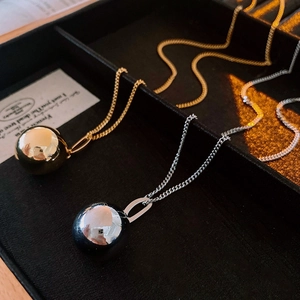 Close-up of gold and silver ball pendant necklaces on a black velvet jewelry tray