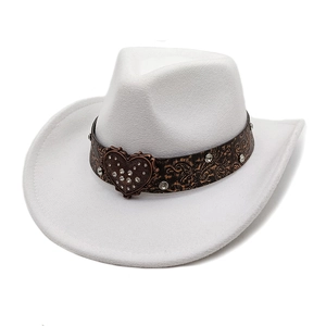 Close-up of heart-shaped rhinestone buckle on a white wool cowboy hat with leather band