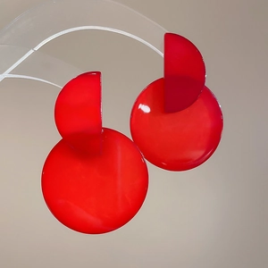 Detail view of red geometric resin earrings with a glossy finish on acrylic stand