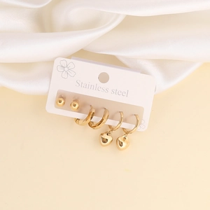 Detail of stainless steel gold earring set featuring heart charms and stud earrings