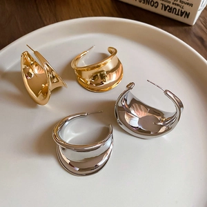 Close-up of wide chunky C-shape hoop earrings in polished gold and silver finishes