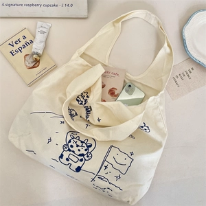 Detail view of large beige canvas tote bag with blue moon-cow print and spacious interior