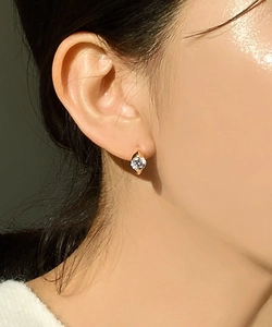 Detail of gold zircon huggie earring showing the brilliant cut stone on a female ear