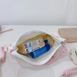 Close-up of pink floral drawstring storage bag with cosmetics and woven cords