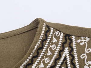 Gros plan sur un chemisier vert olive avec broderie ethnique et texture tissée