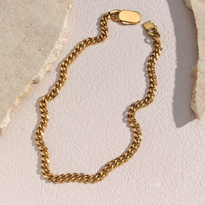 Close-up of golden stainless steel chunky oval link chain on natural stone background