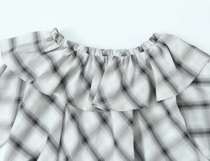 Close-up of elastic neckline with ruffled plaid detail on a grey women's blouse