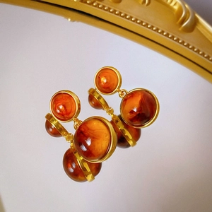Detail view of retro amber resin square earrings with golden metal frames and reflections