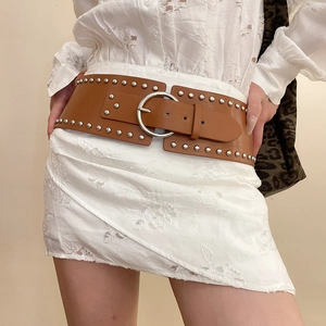 Detail of a wide brown leather belt with silver rivets and large round metal buckle