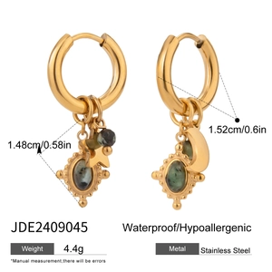 Detail of stainless steel earrings featuring gold star moon charms and green natural stone