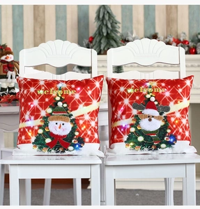 Détails des housses de coussin de Noël rouges à LED avec broderies posées sur chaises blanches