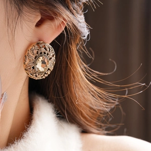 Close-up of vintage gold oval earrings with champagne gemstone worn by a model