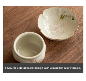 Detail of hand-painted daisy ceramic tea strainer with a separate drip base on wood