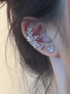 Detailed close-up of butterfly zircon ear cuffs and studs on female model's ear