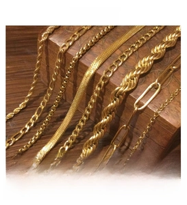 Close-up of assorted gold plated stainless steel chains including Cuban and snake link styles