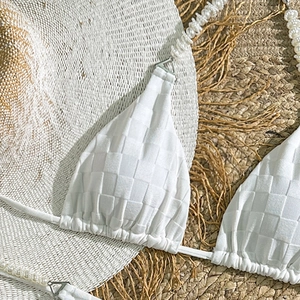 Close-up of white bikini top with checkerboard texture and pearl strap detail