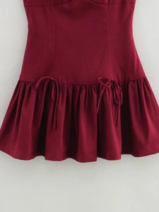 Detailed view of burgundy cotton linen dress with bow ties and ruffled hemline texture