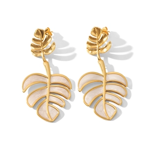 Detail view of gold-plated monstera leaf earrings with white enamel finish
