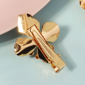Golden metal flower hair clip for girls with a spring back closure on a pastel background