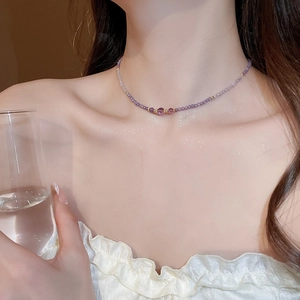Close-up of elegant purple and gold beaded necklace with a central zircon pendant on neck