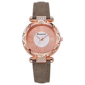 Detail of rose gold watch with rhinestone bezel, white dial and grey leather strap