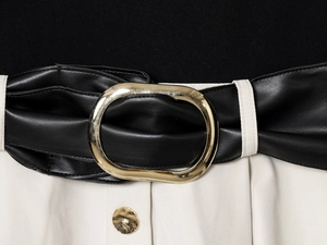Detail of black and white dress with faux leather belt and large oval gold buckle