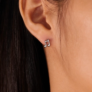 Close-up of a silver music note stud earring on model with detailed metallic finish