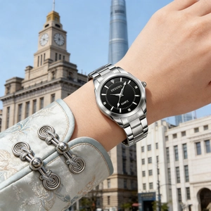 Detail of silver quartz watch with black diamond dial worn on wrist against city skyline