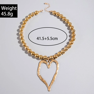 Detailed view of chunky golden bead necklace featuring large hollow heart pendant and extension