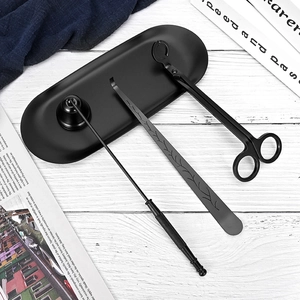Matte black candle tool set with snuffer, trimmer, and tray on a white wooden table
